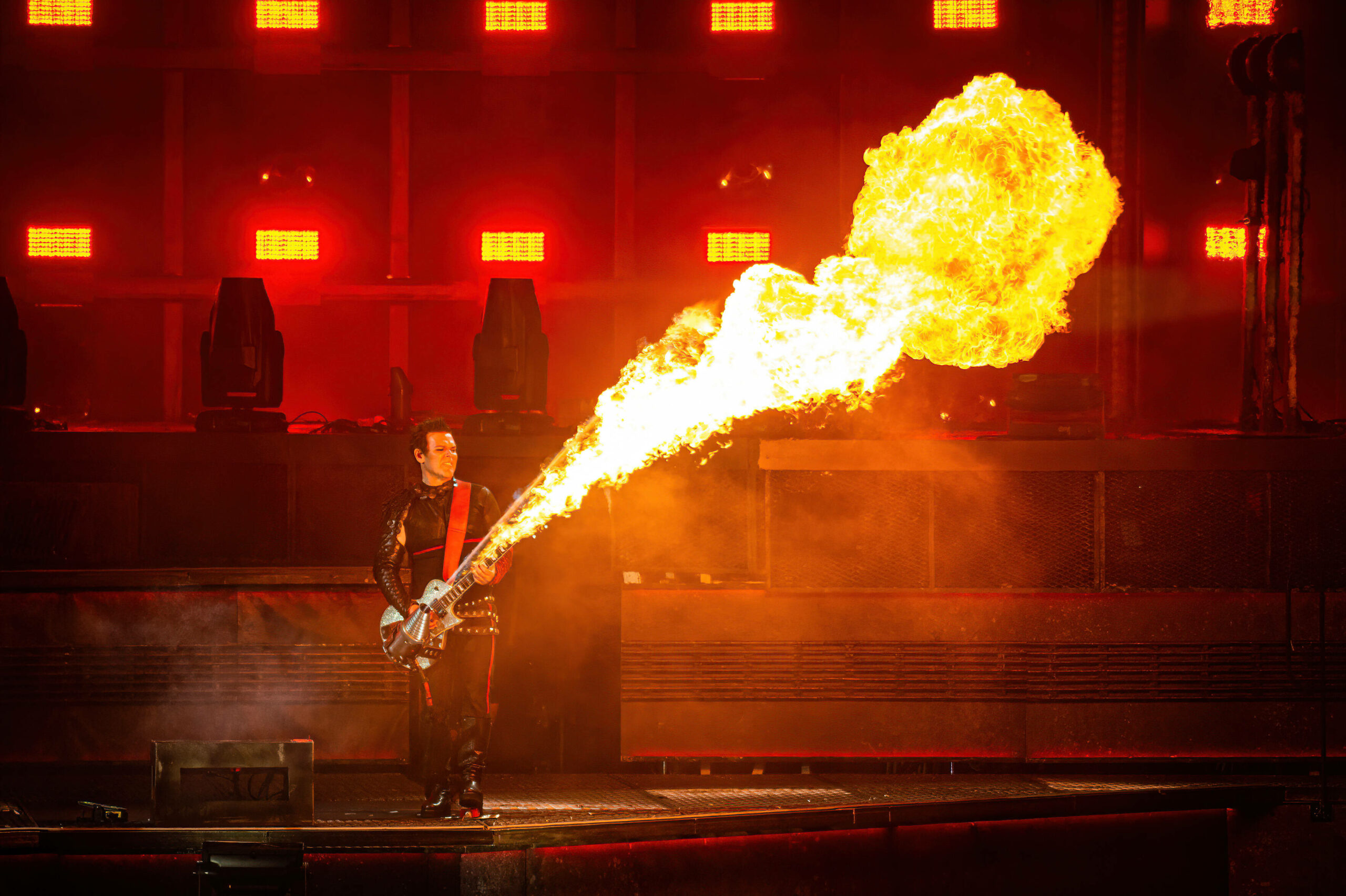Rammstein-Gitarrist Richard Kruspe bei einem Konzert in Dänemark im Jahr 2022, aus dem Hals der Gitarre schießt ein Flammenstrahl