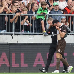 Manolis Saliakas wird von Physio James Morgan vom Feld geführt.