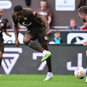St. Paulis Oladapo Afolayan im Zweikampf mit Matthias Zimmermann und Andre Hoffmann vom 1. FC Kaiserslautern.