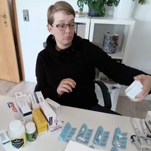 Lara Schaffrinna sitzt in ihrer Wohnung, vor sich zahlreiche Medikamente