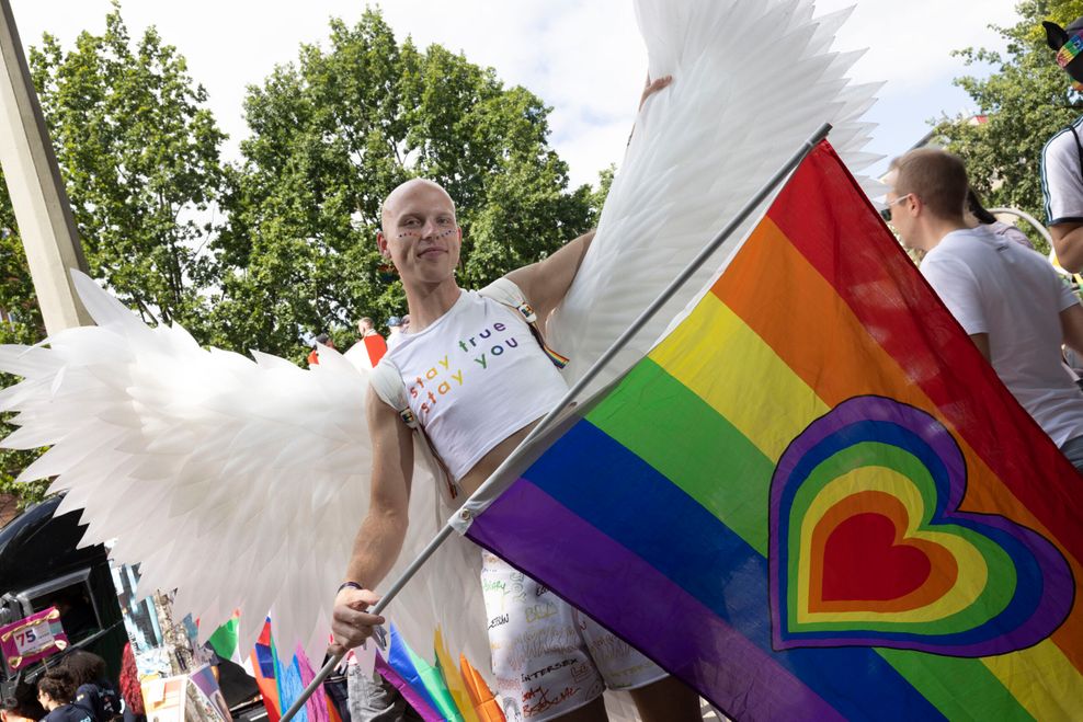 Jonas (26) reist aktuell in Deutschland herum und nimmt an den verschiedenen CSD-Demos teil. Mit im Gepäck seine Engelsflügel, die eine Freundin aus Verpackungsmaterial gebastelt hat. „Ist alles recycelt, soll ja auch nachhaltig sein!“