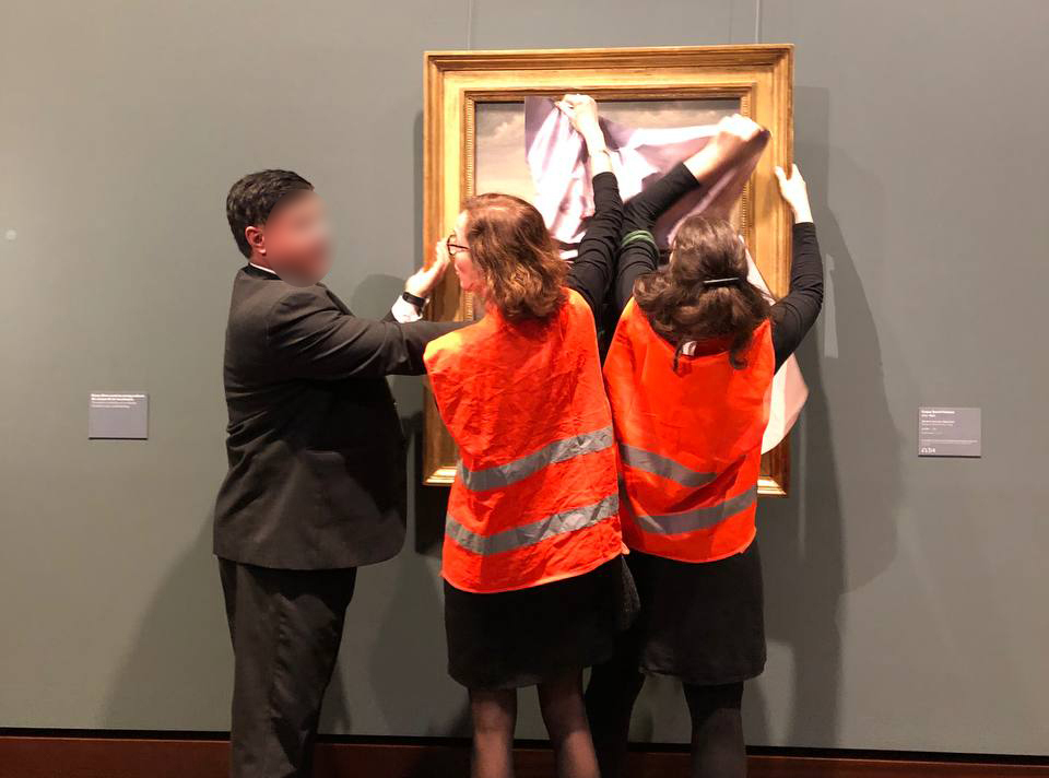 Aktivisten der „Letzten Generation“ versuchen in der Kunsthalle ein Gemälde mit einem Poster zu überkleben.