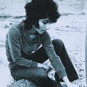 Man sieht die junge Semra Ertan auf einem Stein sitzen, das Foto ist schwarz/weiß.