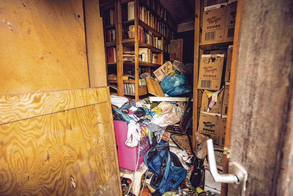 Blick durch die Eingangstür in das zugemüllte Gebäude. Dort lagern auch Hunderte Bücher in Regalen.