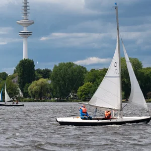 Dunkle Wolken ziehen über den Fernsehturm und zwei auf der Außenalster fahrenden Segelbooten. (Archivbild)