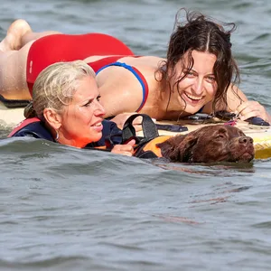Svenja Harrer (r, auf dem Surfbrett), Rettungsschwimmerin der Ortsgruppe Reichertshofen in Bayern, Ulrike Strauß-Kowalski, Wasserwacht Hundeführerin, und Labradorhündin Nala, eine ausgebildete Wasserrettungshündin