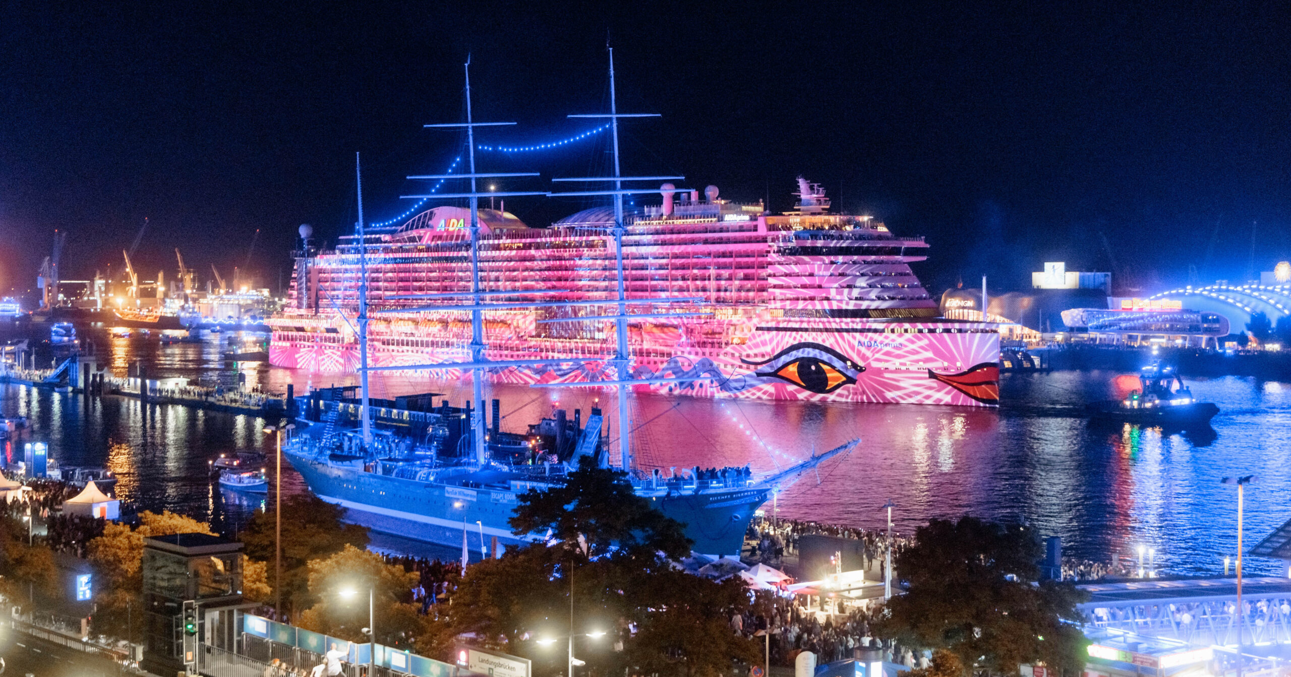 Das Kreuzfahrtschiff AIDAprima wird im Rahmen einer Kunstaktion des Lichtkünstlers Michael Batz bei den Cruise Days 2022 mit farbigem Licht und Mustern angestrahlt.