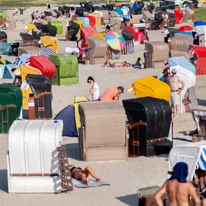 Zahlreiche Touristen sitzen bei spätsommerlichen Wetter in Strandkörben an der Nordseeküste.