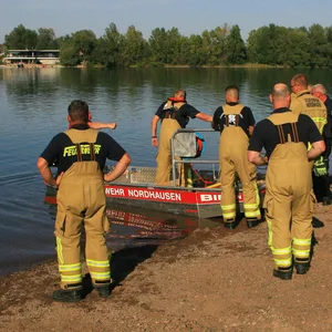 Einsatzkräfte der Feuerwehr stehen am Sundhäuser See (Archivbild).