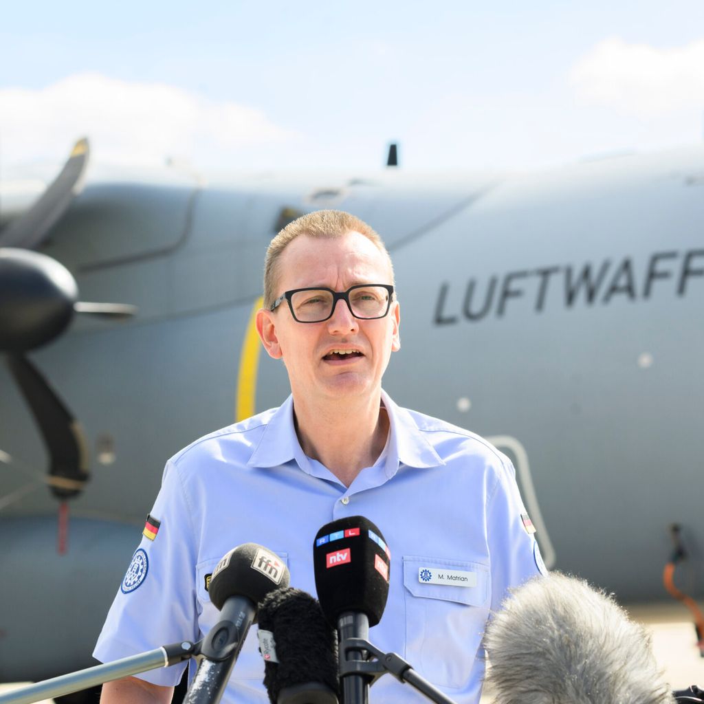 Michael Matrian, Referatsleiter Einsatz des THW Landesverband Niedersachsen Bremen, spricht am Fliegerhorst Wunstorf vor einem Transportflugzeug Airbus A400M der Luftwaffe.