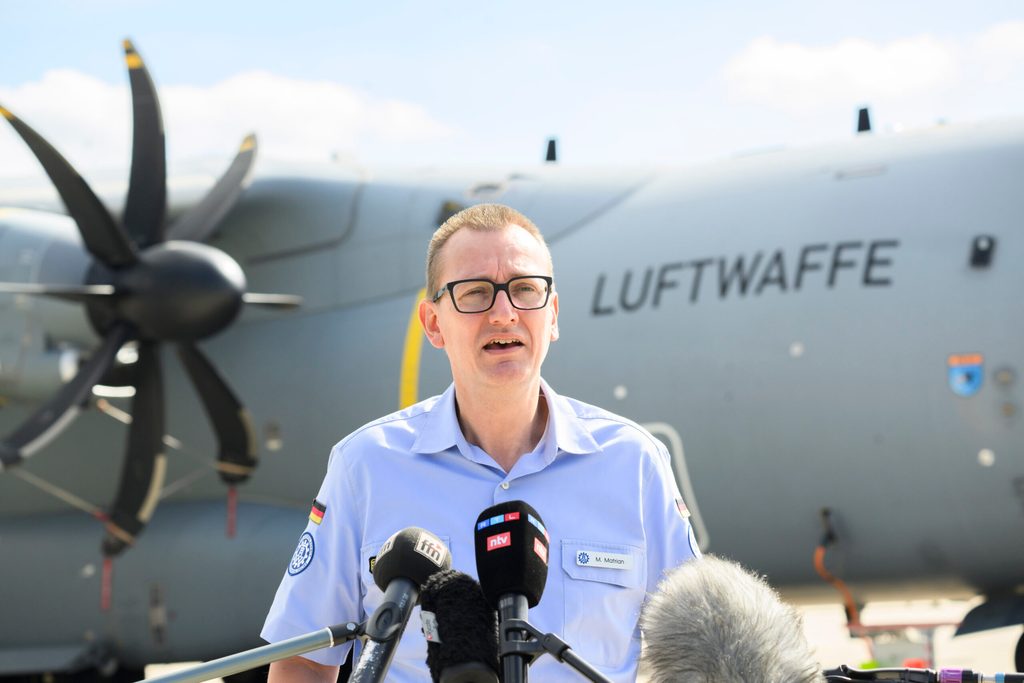 Michael Matrian, Referatsleiter Einsatz des THW Landesverband Niedersachsen Bremen, spricht am Fliegerhorst Wunstorf vor einem Transportflugzeug Airbus A400M der Luftwaffe.