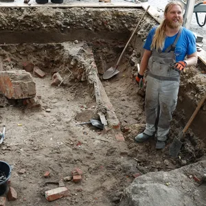 Fabian Schwenn, Grabungsdokumentar für die archäologische Untersuchung auf dem Joseph-Carlebach-Platz, steht auf der Ausgrabungsfläche.