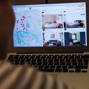 Ein User sitzt am Laptop, zu sehen ist eine Seite des Portals „Airbnb“.