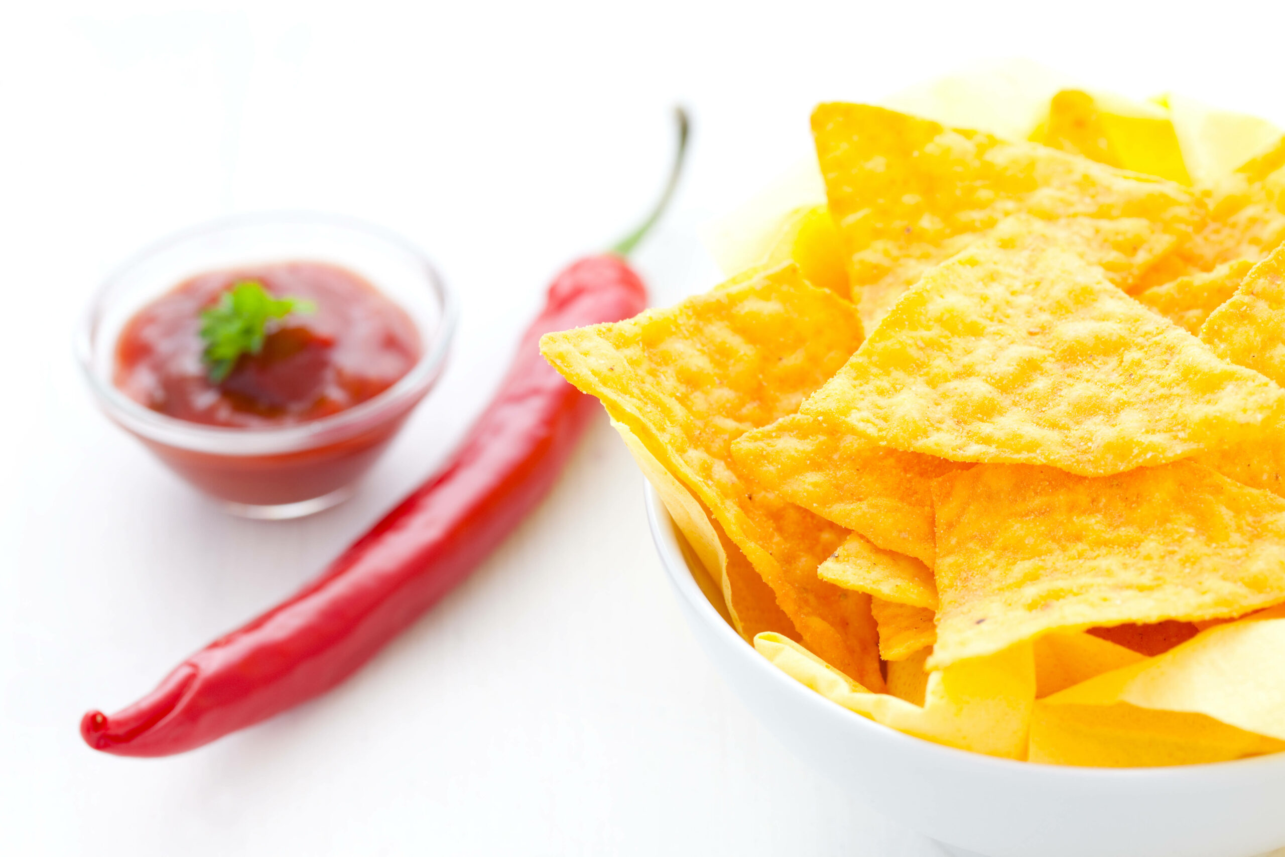 Tortillachips liegen rechts neben einer Chilischote und Chilisoße. (Symbolbild)