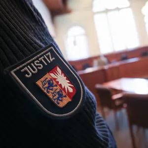 Ein Justizbeamter steht im Gerichssaal im Landgericht Flensburg.