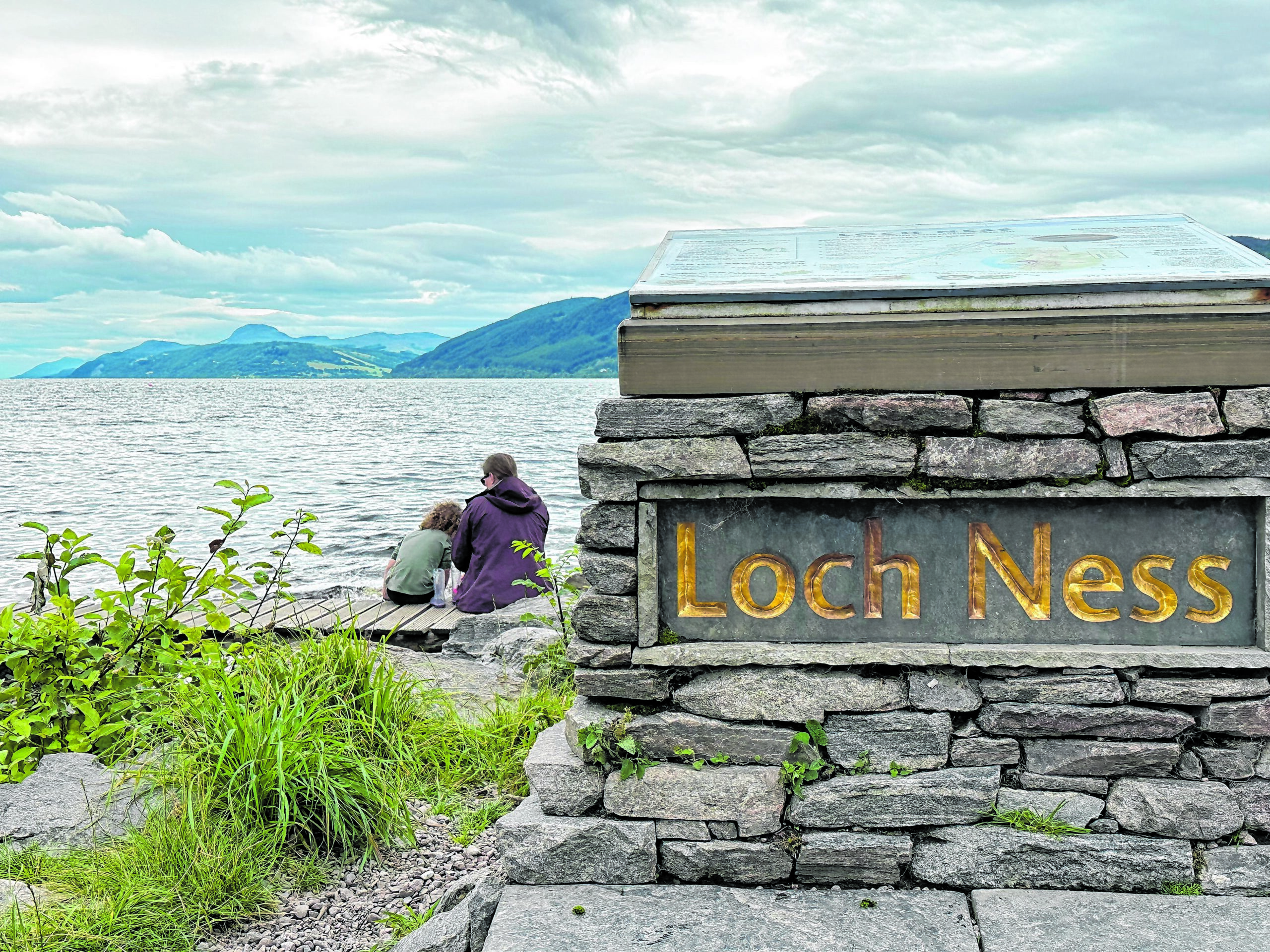 Zwei Menschen sitzen am Ufer des Sees Loch Ness