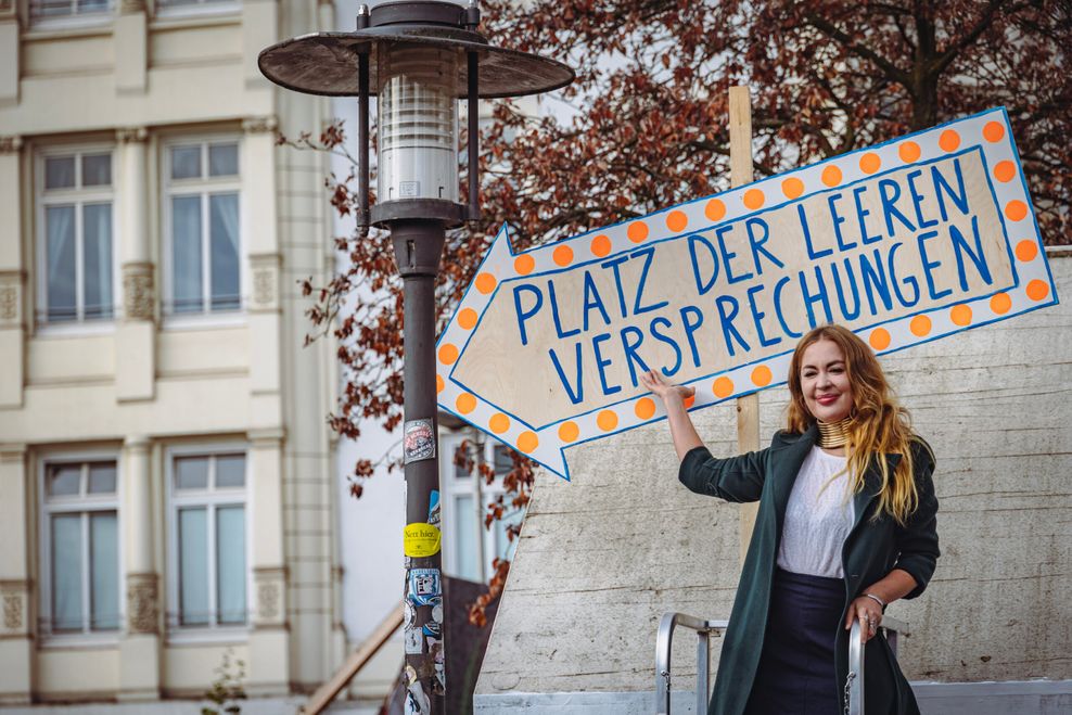 Aksana (39) von der Initiative und ehemalige Bewohnerin enthüllte mit einer Performance das Schild und begoss das Grundstück mit Champagner.