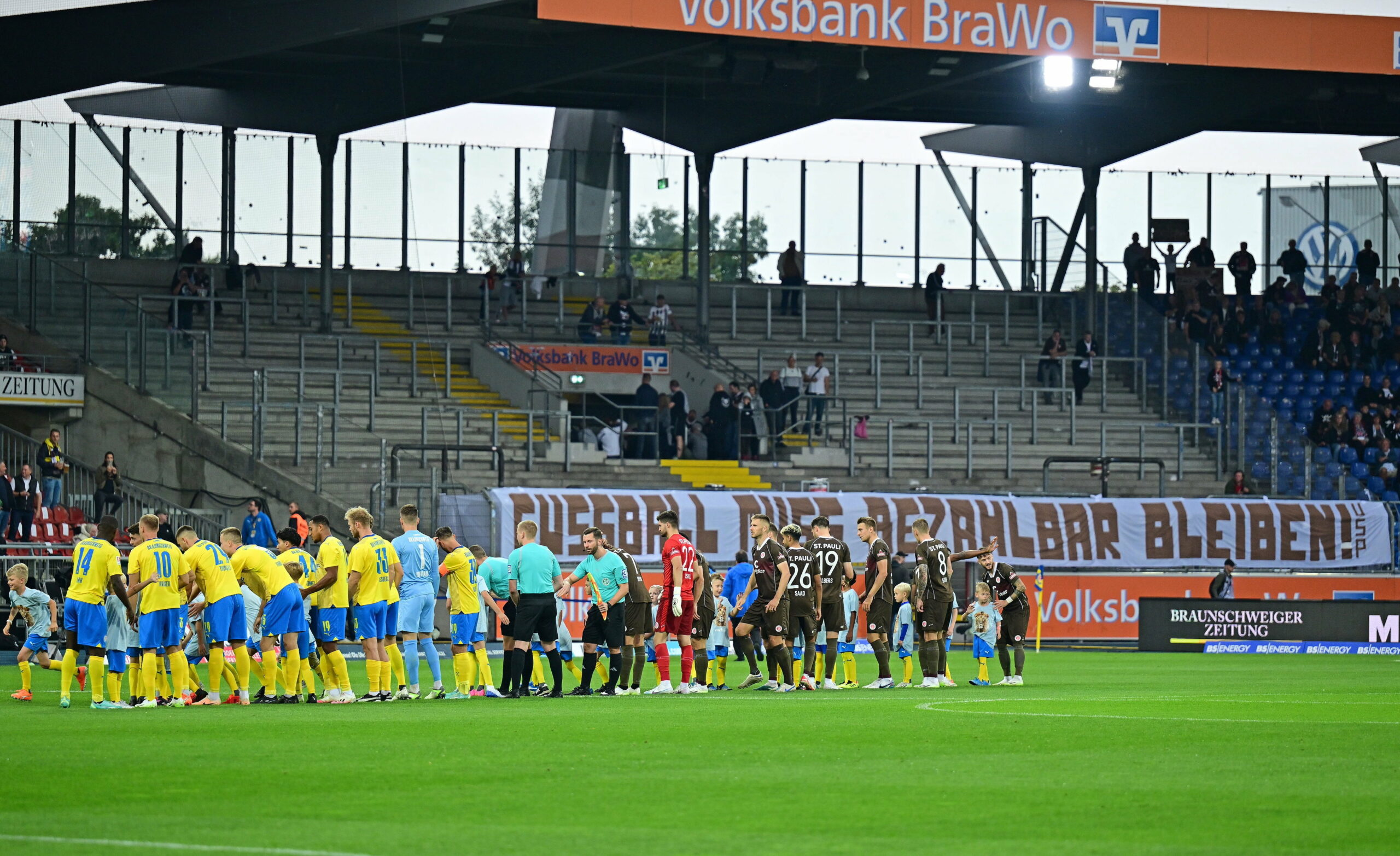 Die Mannschaften von St. Pauli und Braunschweig vor der leeren Fankurve