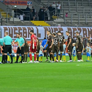 Die Mannschaften von St. Pauli und Braunschweig vor der leeren Fankurve