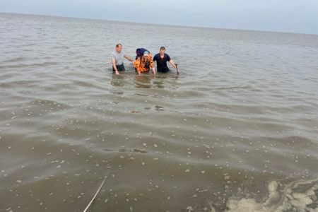 Zwei Helfer holen einen Wattwanderer aus dem Wasser