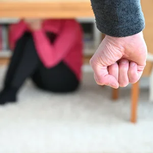Symbolbild Gewalt gegen Frauen: Im Vordergrund ein Mann mit geballter Faust, hinten eine verängstigte Frau