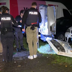 Polizisten stehen vor dem gesprengten Automaten.