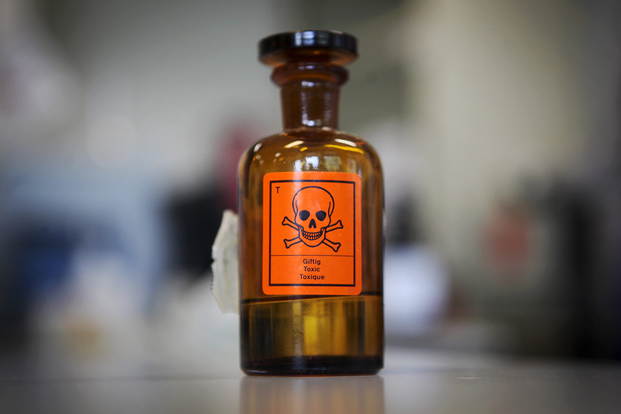 Eine Glasflasche mit einem Aufkleber für „Giftig“ und einem Totenkopf-Symbol steht auf einem Tisch. (Symbolbild)
