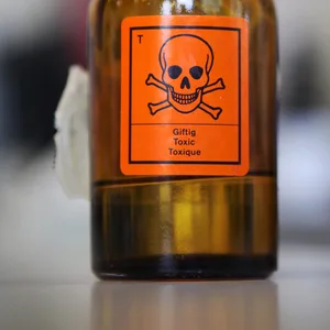 Eine Glasflasche mit einem Aufkleber für „Giftig“ und einem Totenkopf-Symbol steht auf einem Tisch. (Symbolbild)