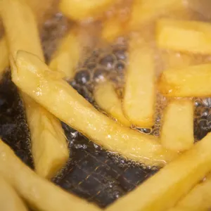Pommes werden in einem Imbiss in Pflanzenöl frittiert.