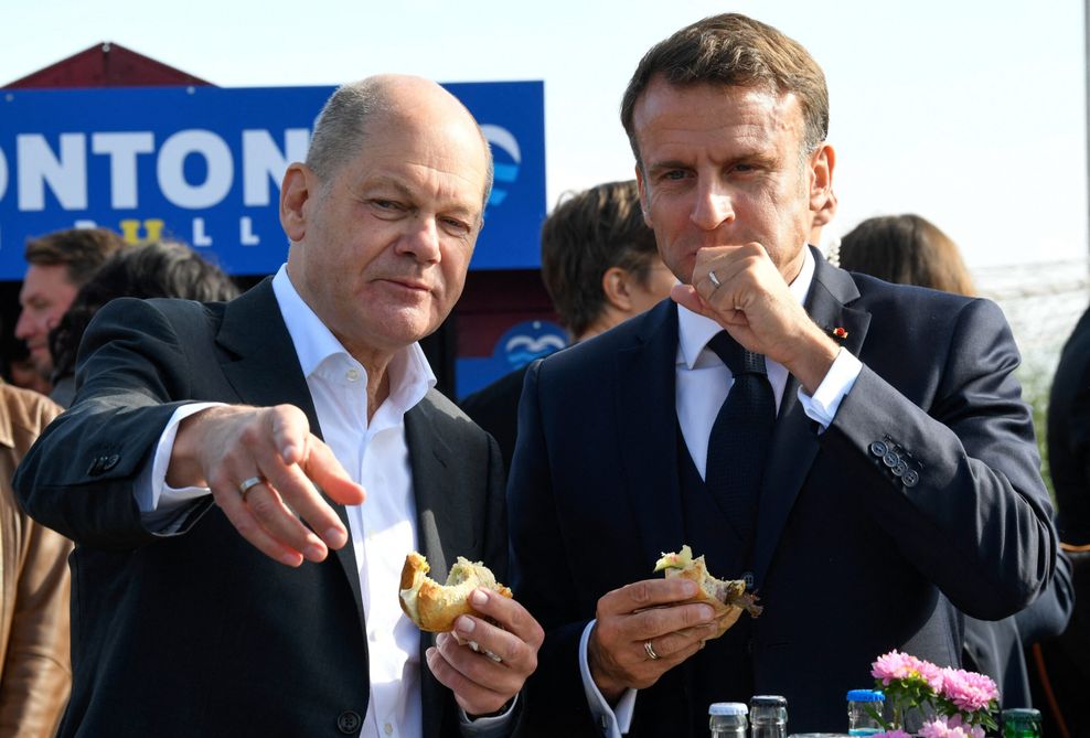 Bundeskanzler Olaf Scholz (SPD) und Frankreichs Präsident Emmanuel Macron (r) essen gemeinsam in Blankenese an der Elbe ein Fischbrötchen.