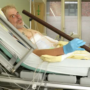 Patient Frank Vaorin liegt im Krankenhausbett und hält die Zaunstange in der Hand, die seinen Körper durchbohrte.