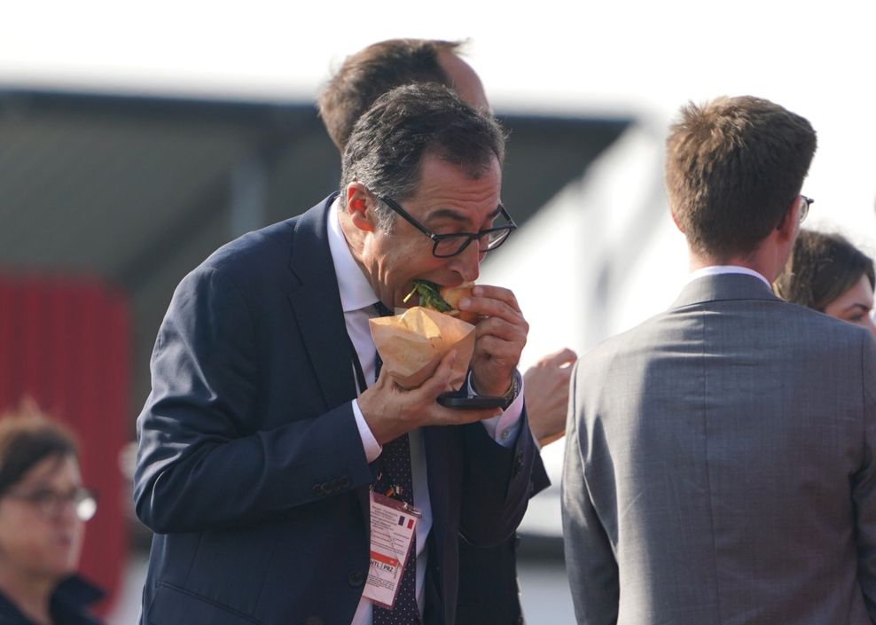 Cem Özdemir (Bündnis 90/Die Grünen), Bundesminister für Ernährung und Landwirtschaft, isst ein Fischbrötchen während eines gemeinsamen Mittagsimbisses an einer Fischbude.