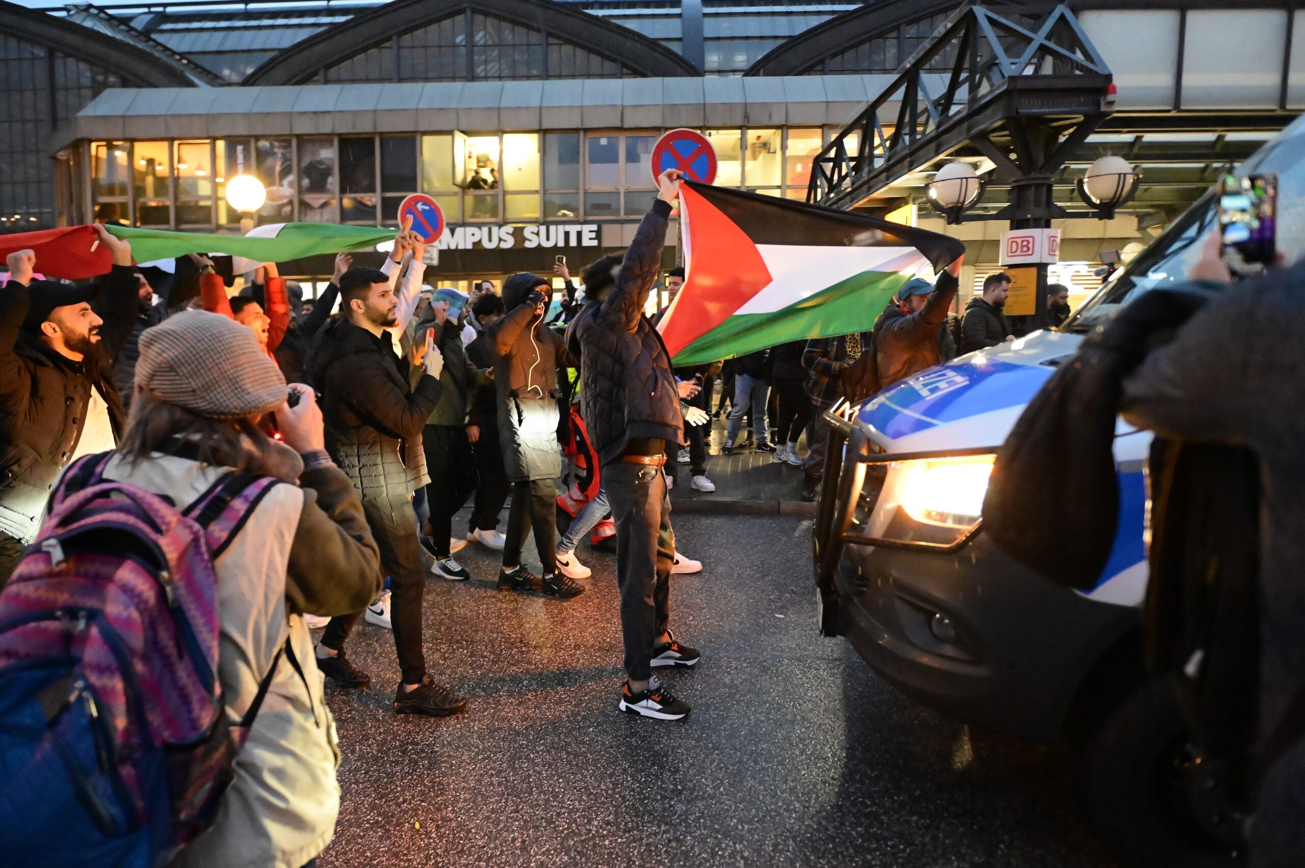 Teilnehmer der pro-palästinensischen Kundgebung vor dem Hauptbahnhof stellen sich vor ein Polizei-Fahrzeug.