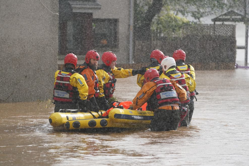 Mitarbeiter der Rettungsdienste bringen Anwohner in Sicherheit, während der Sturm „Babet“ über das Land fegt.