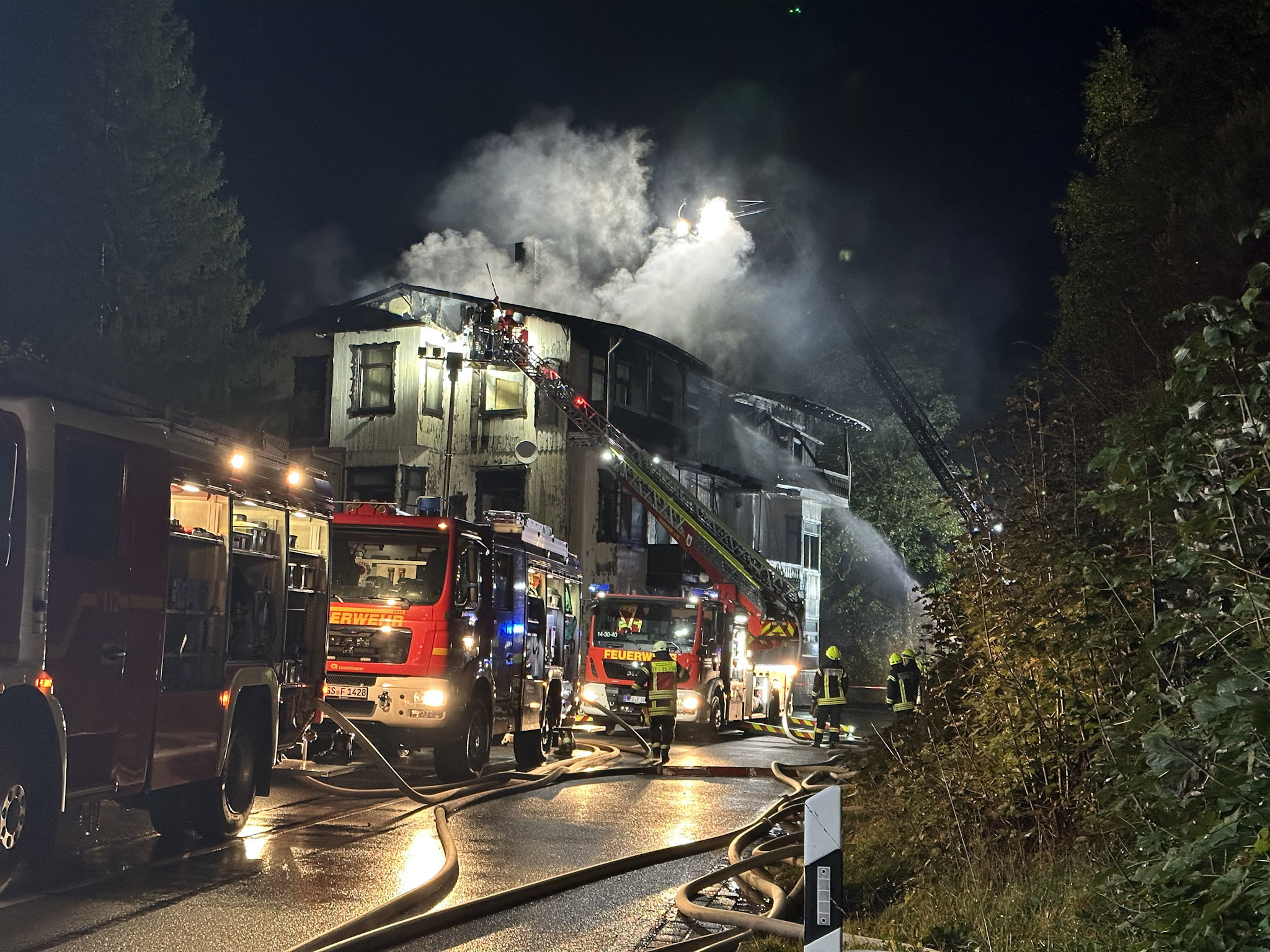 Mehrere Einsatzwägen der Feuerwehr stehen vor dem brennenden historischen Gebäude bei Goslar.