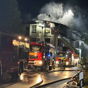 Mehrere Einsatzwägen der Feuerwehr stehen vor dem brennenden historischen Gebäude bei Goslar.