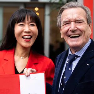 Gerhard Schröder (.r), Alt-Bundeskanzler, und seine Frau So-yeon Schröder-Kim stehen nach der Verleihung vor dem Kurt-Schumacher-Haus vor Medienvertretern.