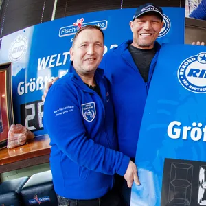 Axel Schulz, ehemaliger Profiboxer (2.v.l.), und André Domke (1.v.l), Fischsommelier und Fischhändler stehen am Weltrekord. Sie produzierten das größte Bismarkheringsbrötchen.