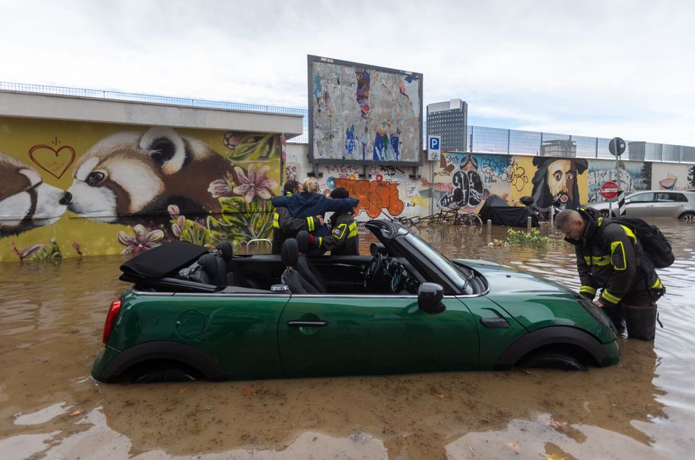 Rettungskräfte heben eine Frau aus einem Mini-Cabrio.