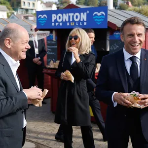 Olaf Scholz (l.), Emmanuel Macron (r.) und dessen Ehefrau Brigitte (m.) haben Spaß, als sie sich zum Mittagessen ein Fischbrötchen genehmigen.
