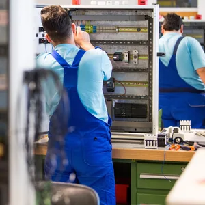 Geflüchtete arbeiten im Ausbildungszentrum der Siemens Professional Education an der Verdrahtung eines Schaltschranks.