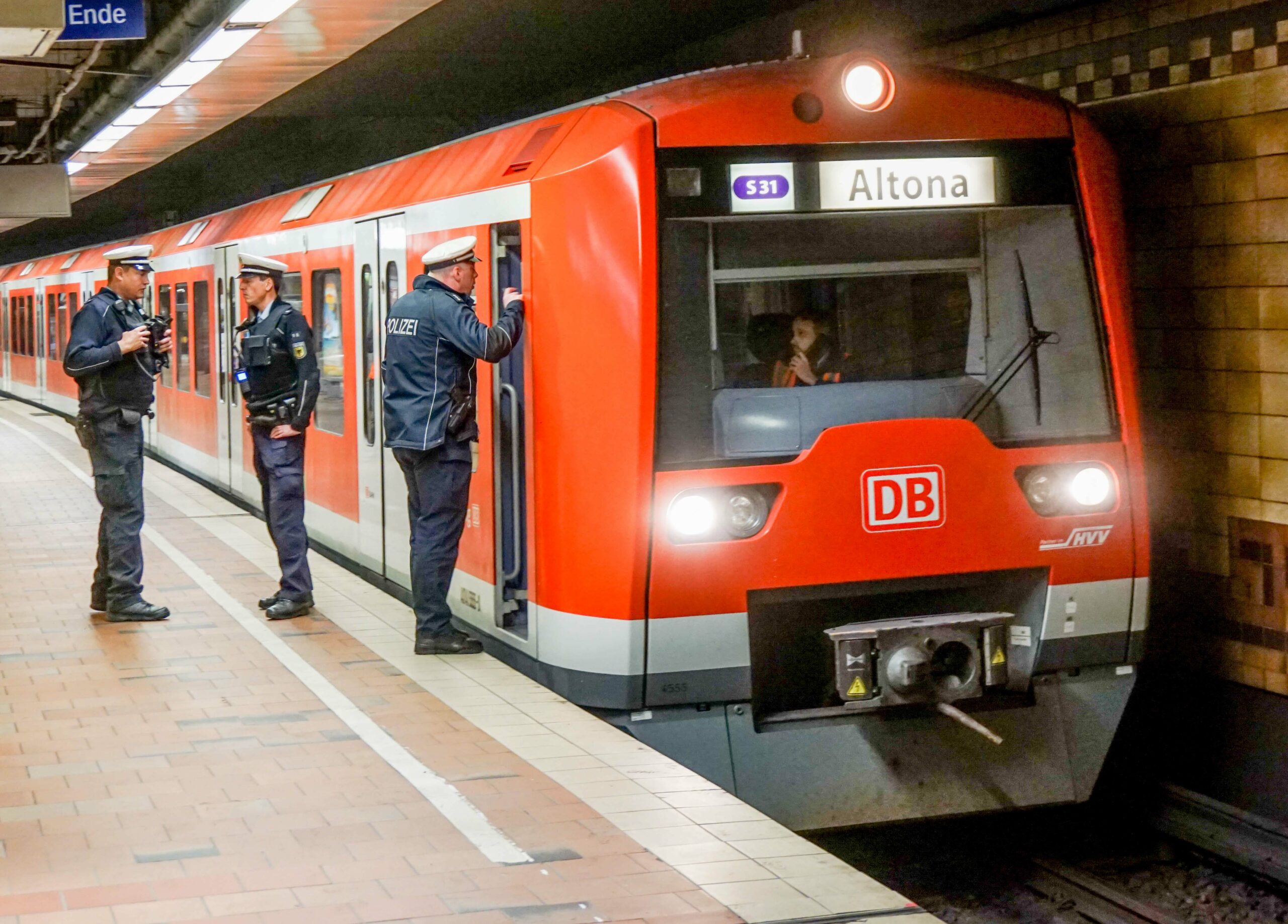 Drei Polizisten stehen neben einem Zug der Linie S31 im Bahnhof Altona.