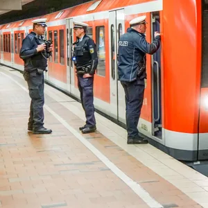 Drei Polizisten stehen neben einem Zug der Linie S31 im Bahnhof Altona.