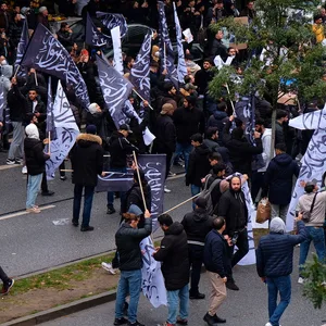 Demonstranten schwenken Flagge mit islamischem Glaubensbekenntnis.