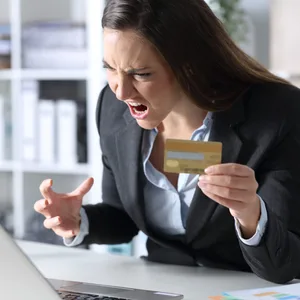 Eine Frau hält ihre Kreditkarte in der Hand und ärgert sich über eine Bestellung im Internet. (Symbolbild)