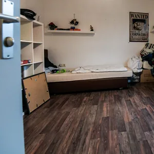 Ein Zimmer mit Bett, Laminatfußboden und Regalen(Symbolbild)