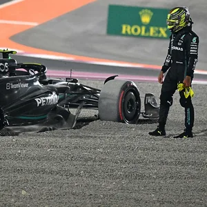 Hamilton guckt auf sein Formel 1-Wagen, welcher nur noch drei statt vier Reifen hat.