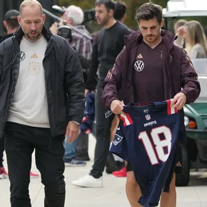 DFB-Spieler Jonas Hofmann mit Patriots-Trikot in den Händen