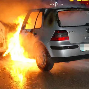 Flammen schlagen aus einem silbernen VW Golf.