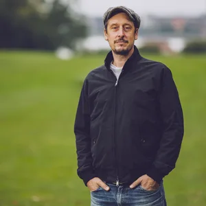 Schauspieler Hans Löw steht im Jenischpark. Im Hintergrund die Elbe.